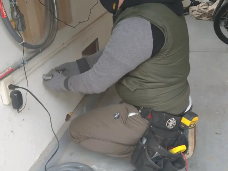 Electrician performing outlet wiring in a Warm Beach garage